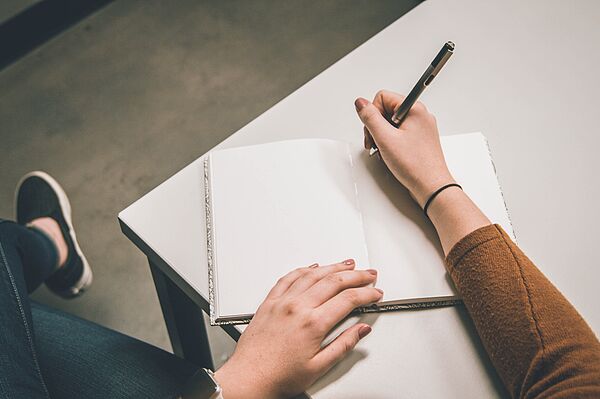 Eine Person hält Stift und Papier