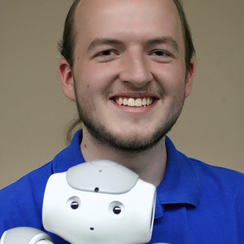Portraitfoto mit einem kleinen humanoiden Roboter auf dem Arm